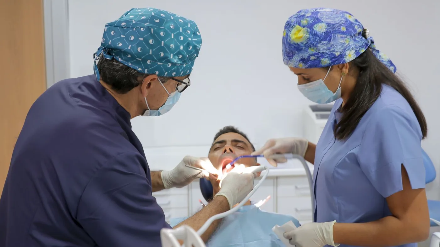 Odontólogo y auxiliar atendiendo a un paciente en el gabinete de Clínica Lahera Dental en Carlet